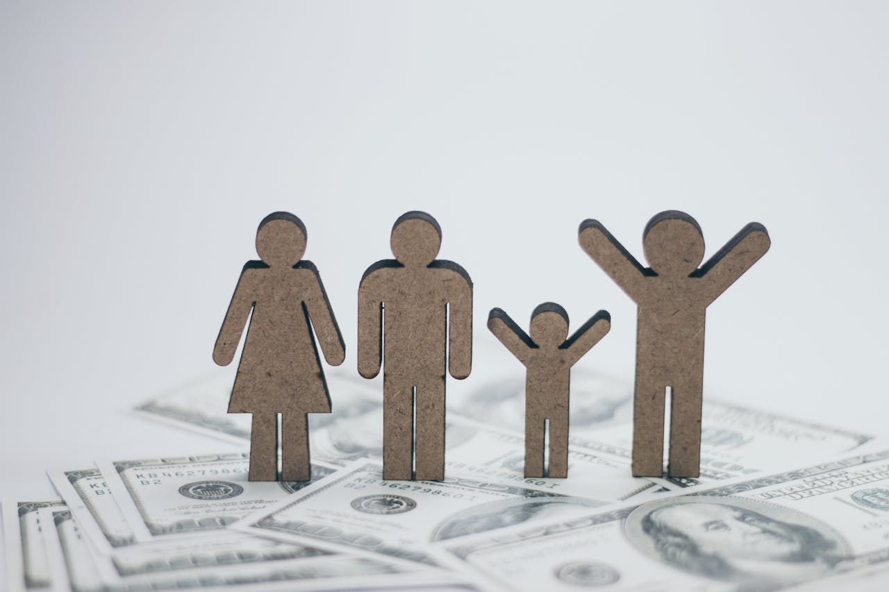 about-us Wooden family figurines on dollar bills symbolizing financial stability.